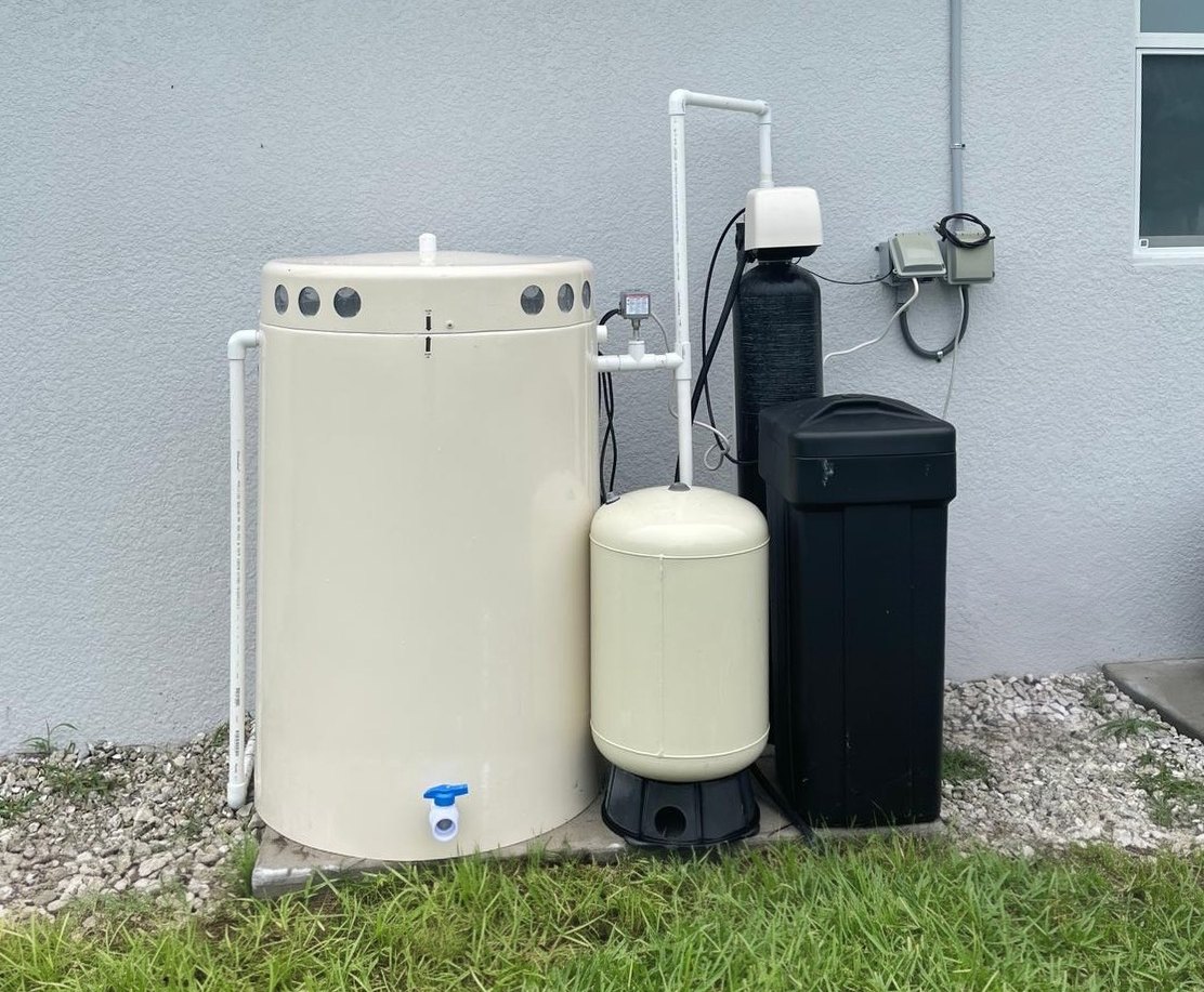 Aeration tank system with a pressure tank, filter tank and brine tank beside a home
