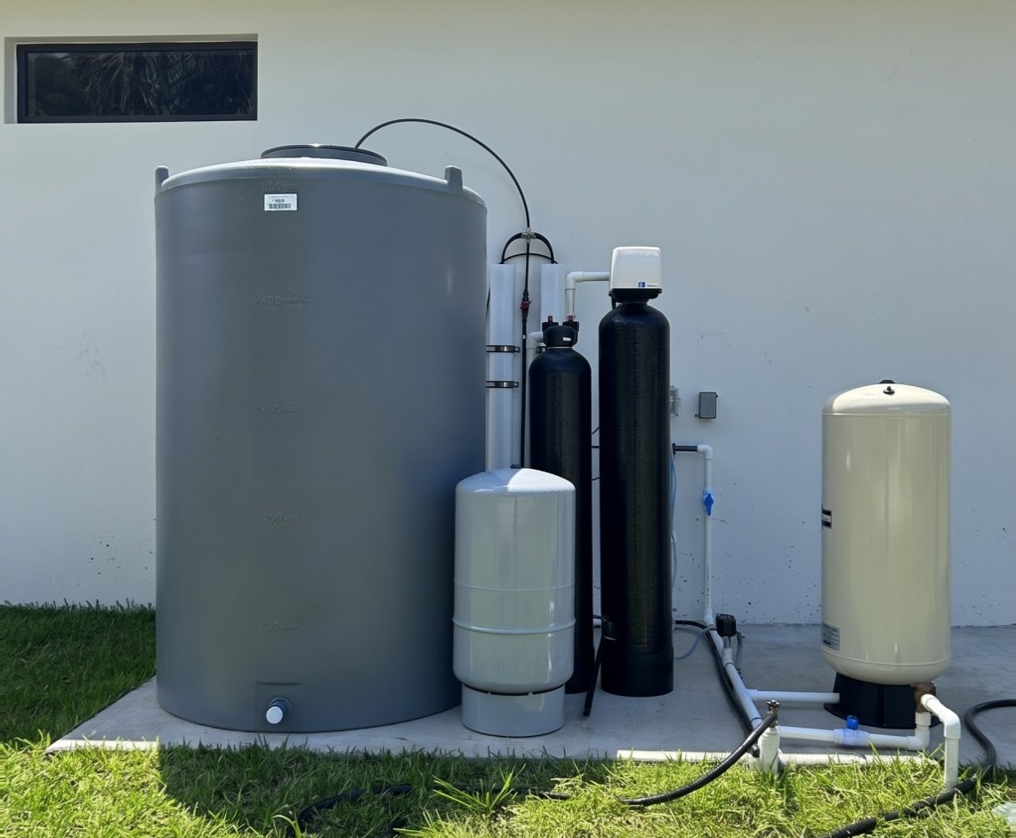 Whole-house reverse osmosis system with a gray storage tank, 2 membrane housings, filter tanks and pressure tanks on a concrete pad